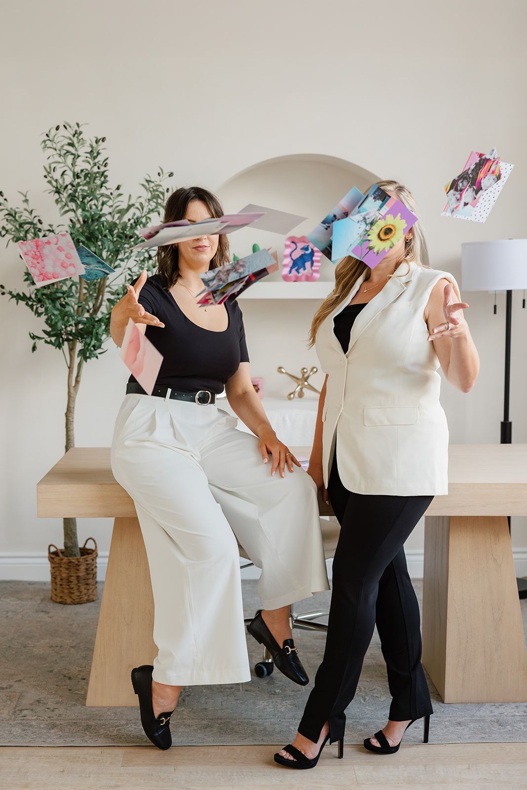 Two women are standing next to each other holding papers in front of their faces.
