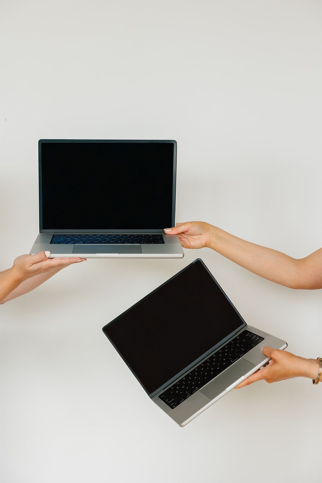 website refresh vs redesign. Two computers being passed to each other