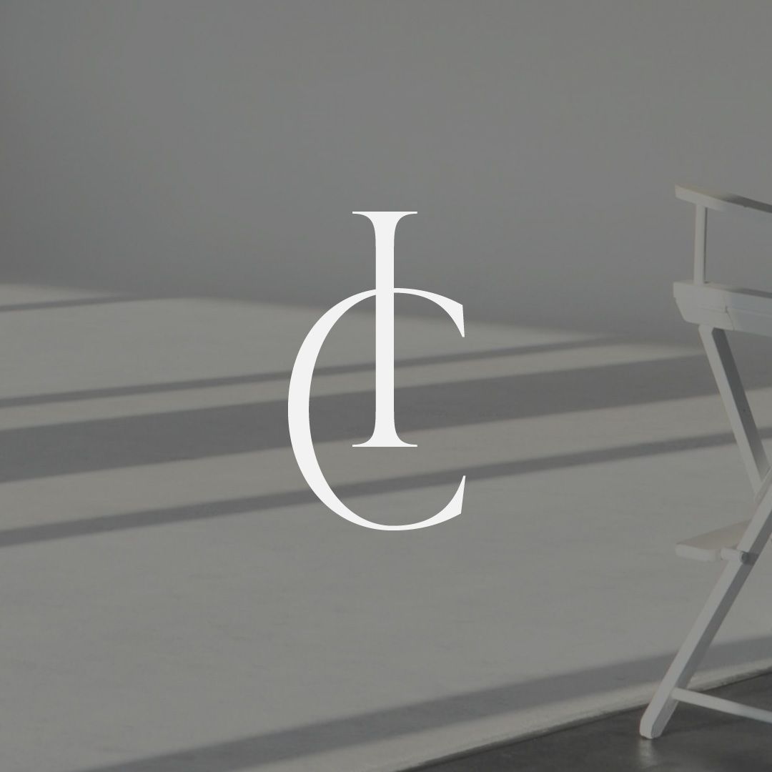 A white director 's chair is sitting in front of a gray wall.