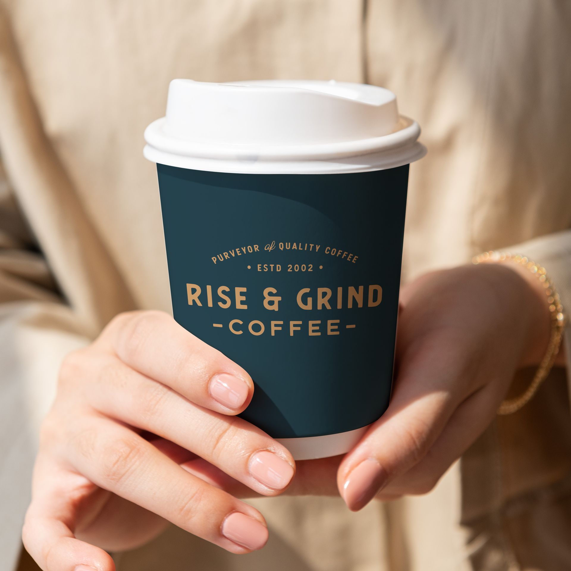 A person is holding a cup of rise & grind coffee