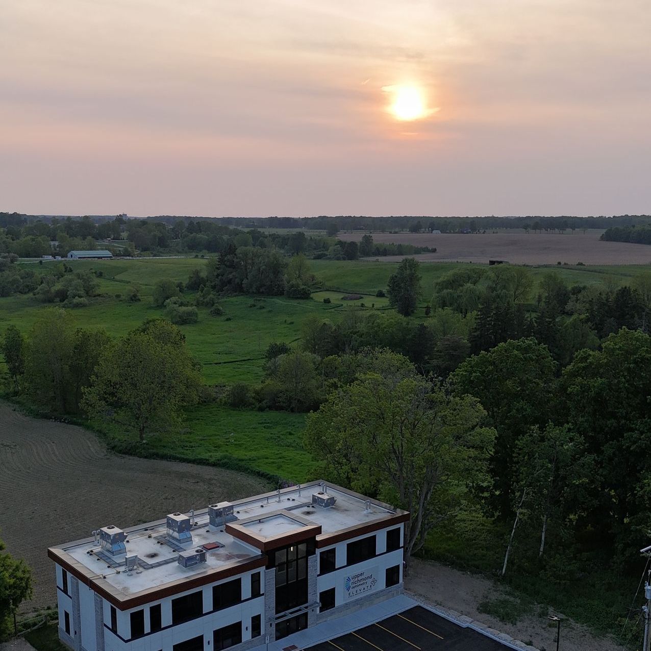 Drone aerial view of a building in the middle of a field at sunset by Lume Creative