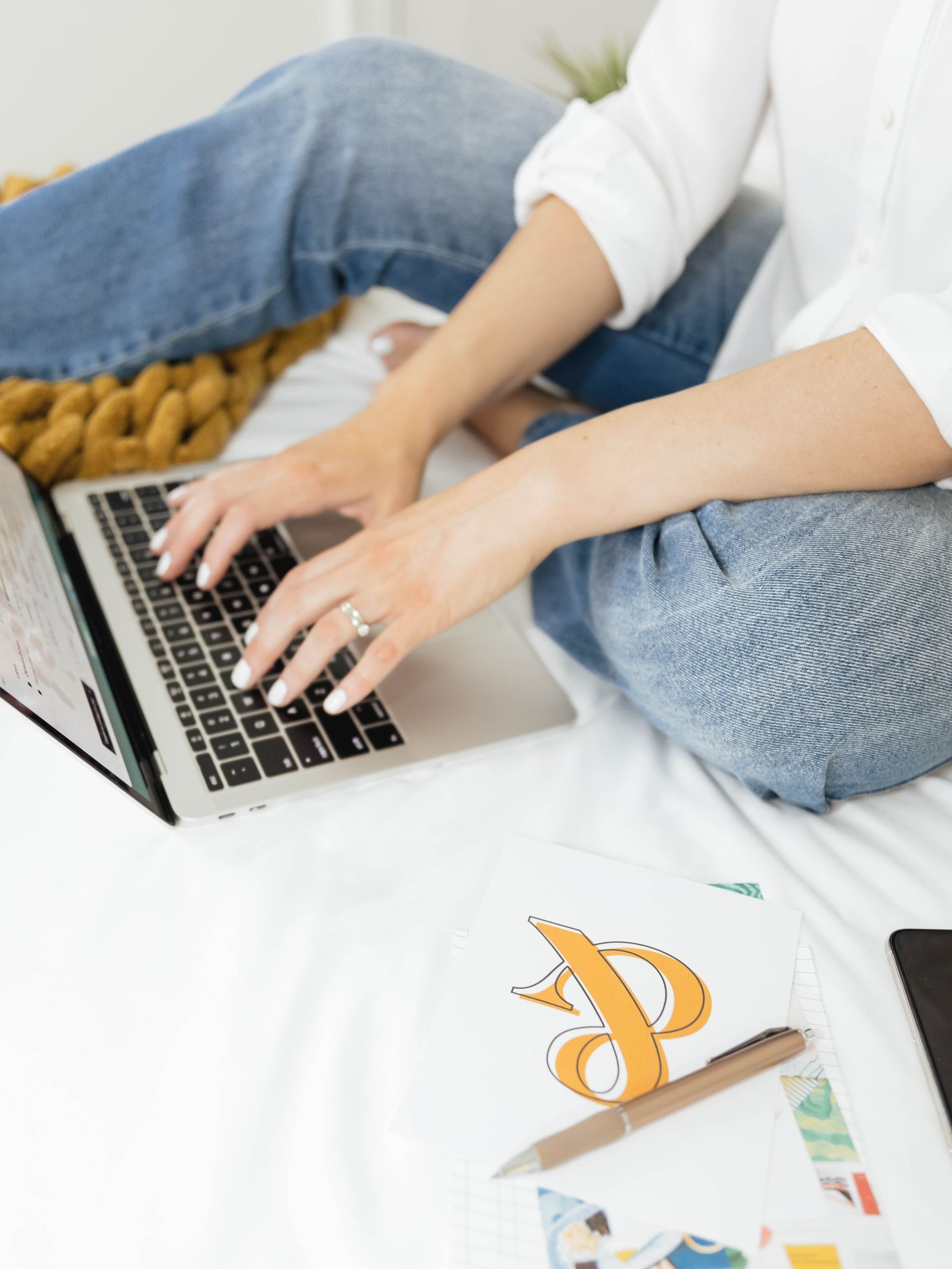 A woman is sitting on a bed using a laptop computer.