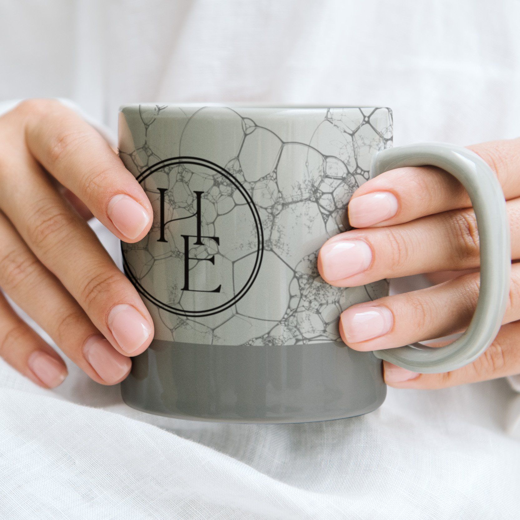 A person is holding a mug with the letter e on it