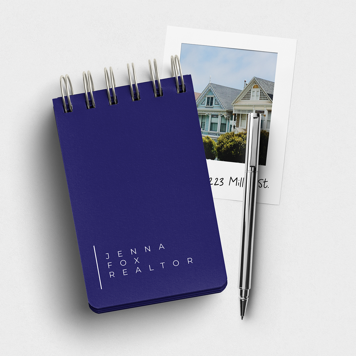 A blue notebook with a pen next to a picture of a house