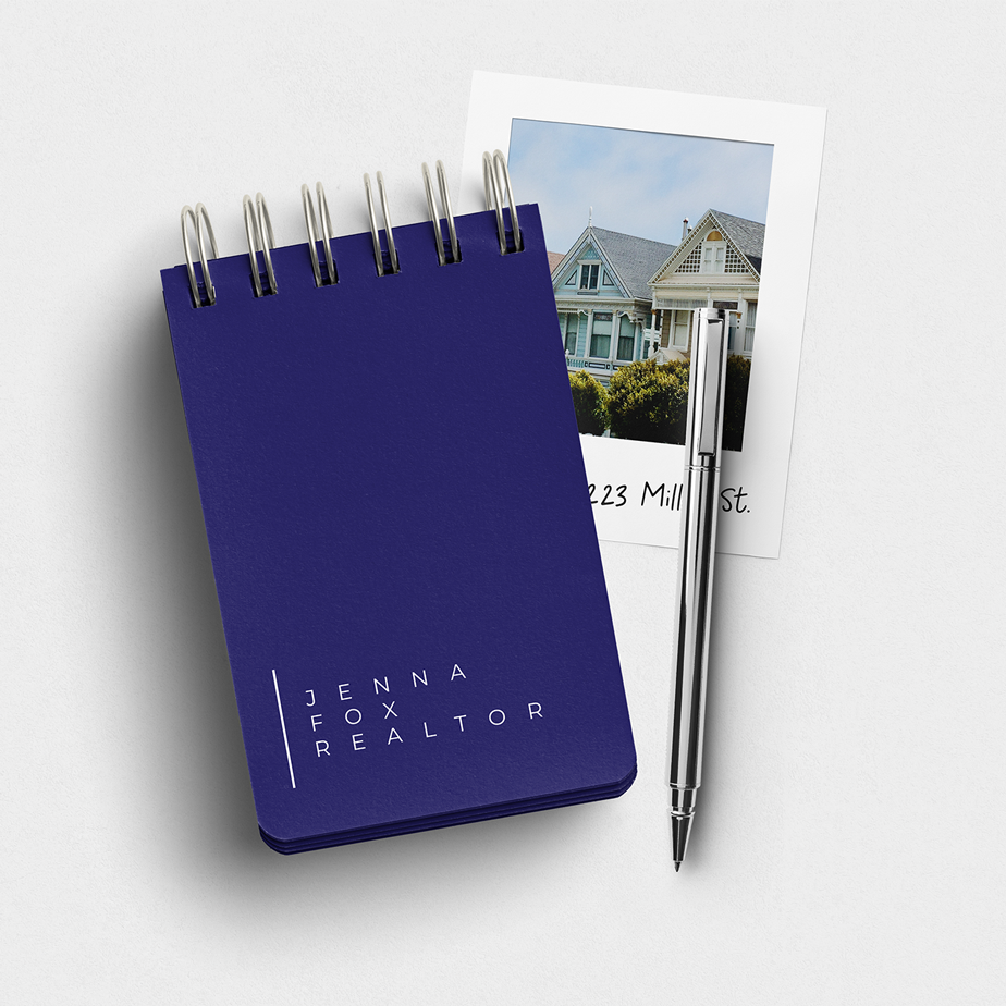 A blue notebook with a pen next to a picture of a house