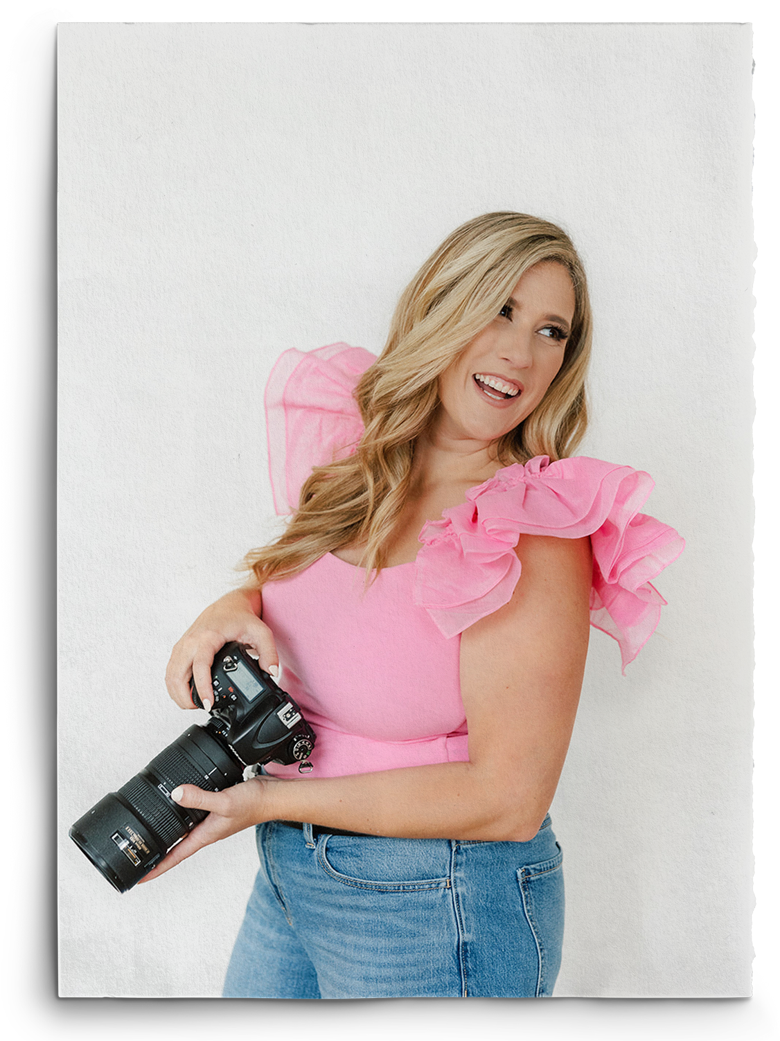 A woman in a pink top is holding a camera.