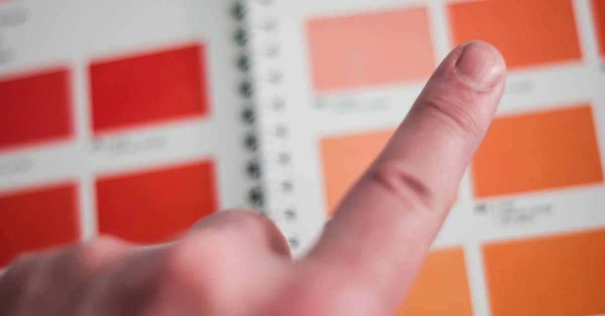 A close up of a person 's finger pointing at a color chart.