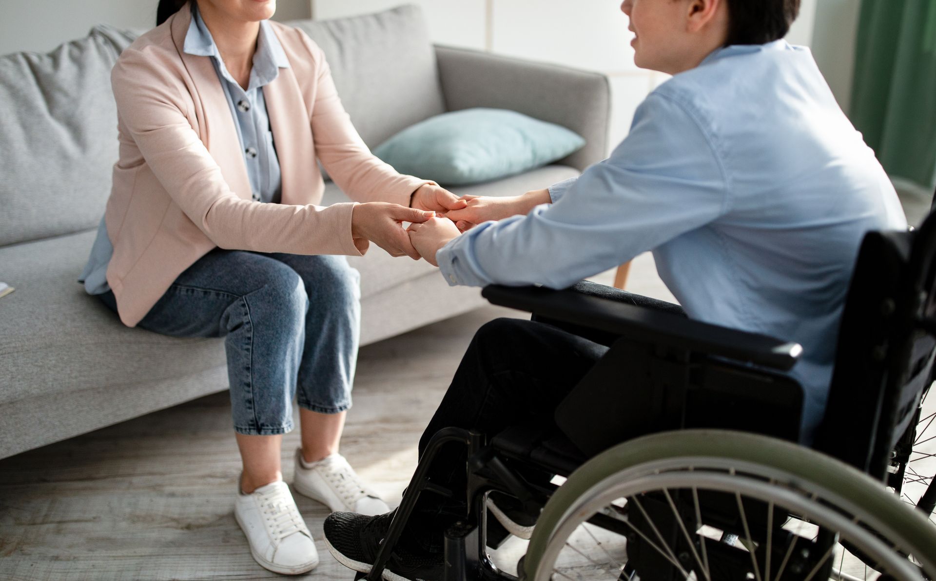 Support worker comforting a teenage boy in a wheelchair during a care visit.