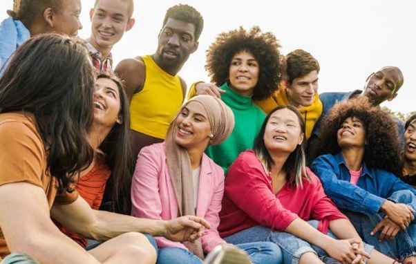 Group of diverse young adults smiling and laughing outdoors.