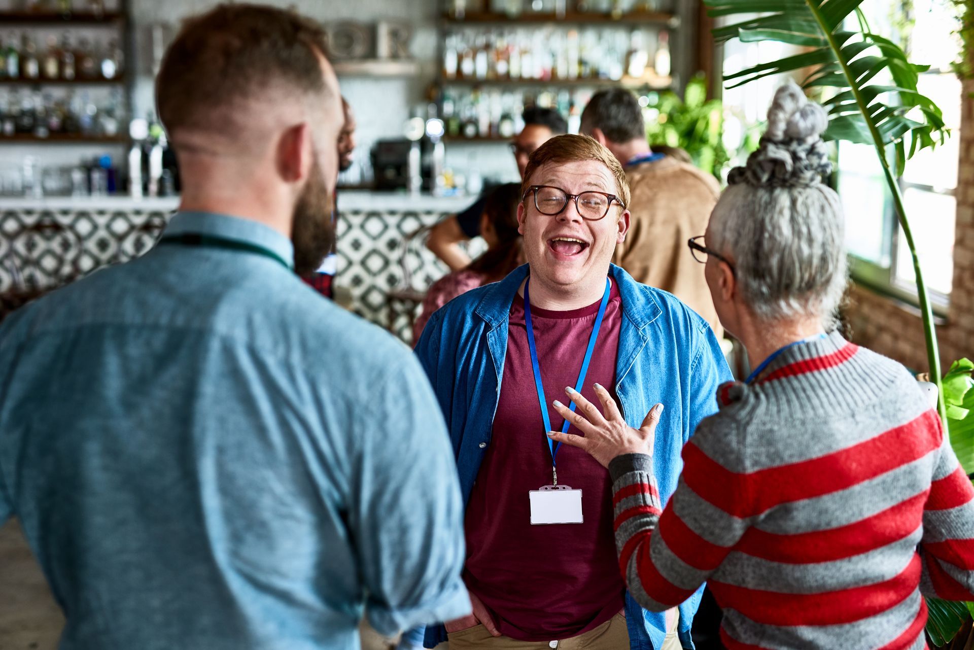 A group of people are standing around talking to each other in a restaurant.