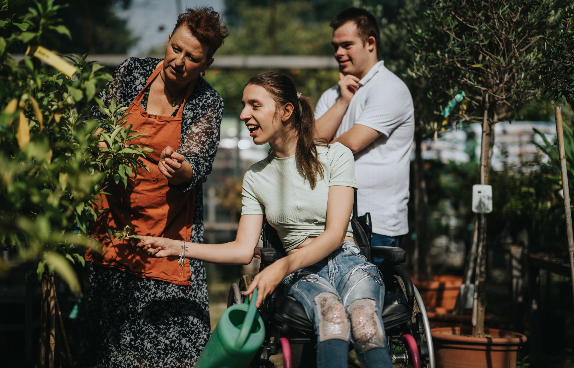 A woman in a wheelchair is watering a plant with a watering can.