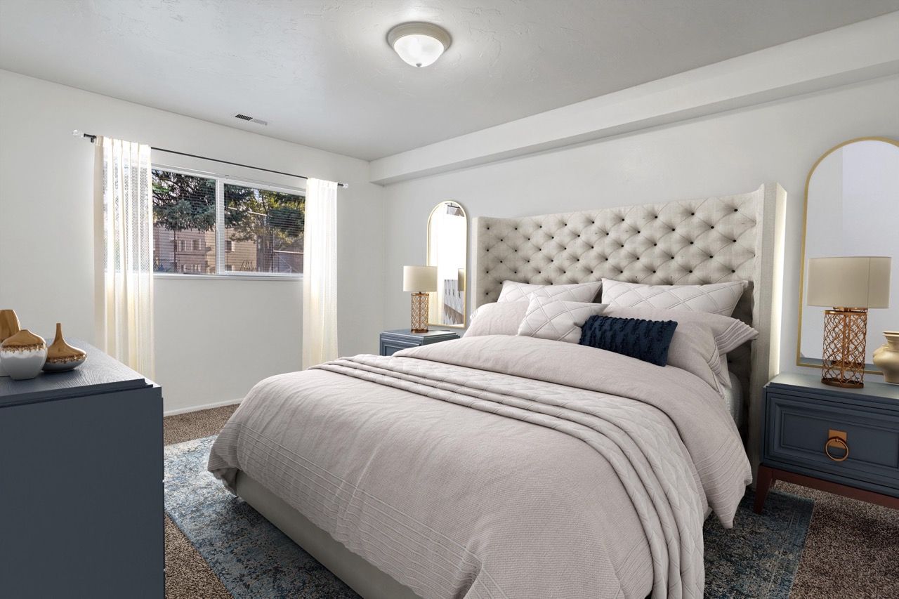 Bedroom in a modern apartment with a tufted headboard, blue nightstands, and a large window.