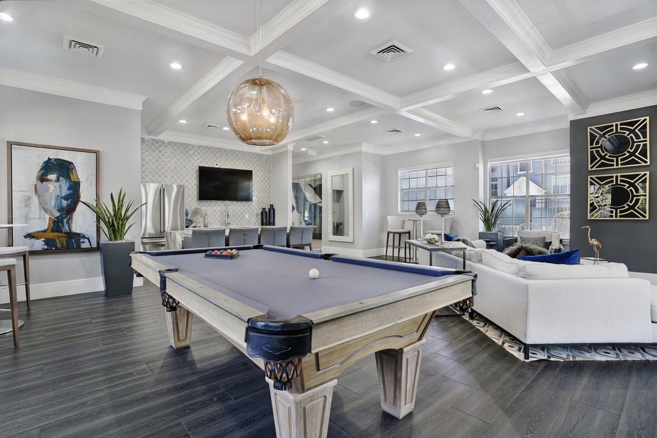 Indoor amenity lounge featuring a pool table, TV, and modern seating.