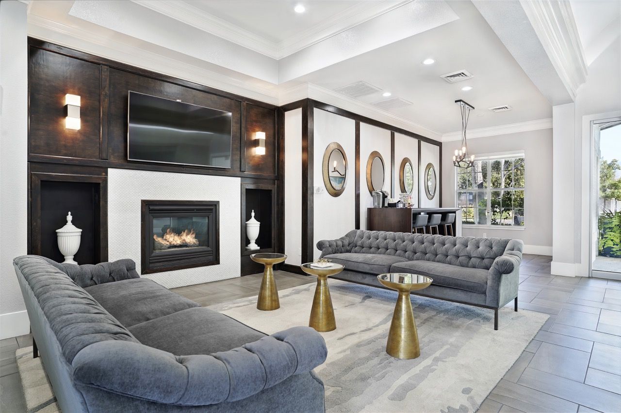 Living room with two tufted gray sofas, a fireplace, and a wall-mounted TV.