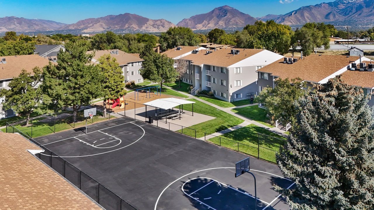 Bird's-eye view of a multifamily community with a basketball court, playground, and green courtyards.
