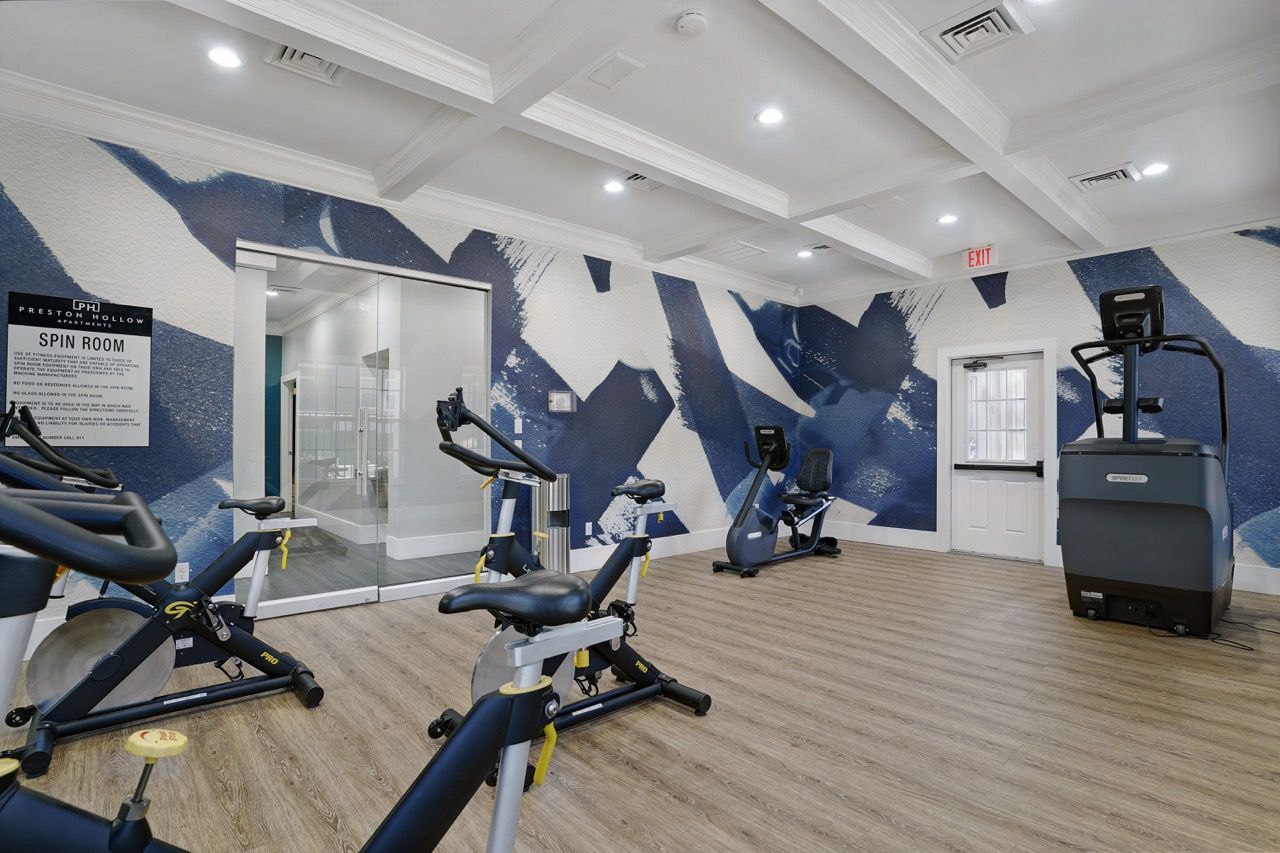 Indoor fitness center with multiple cardio bikes and a blue abstract mural.