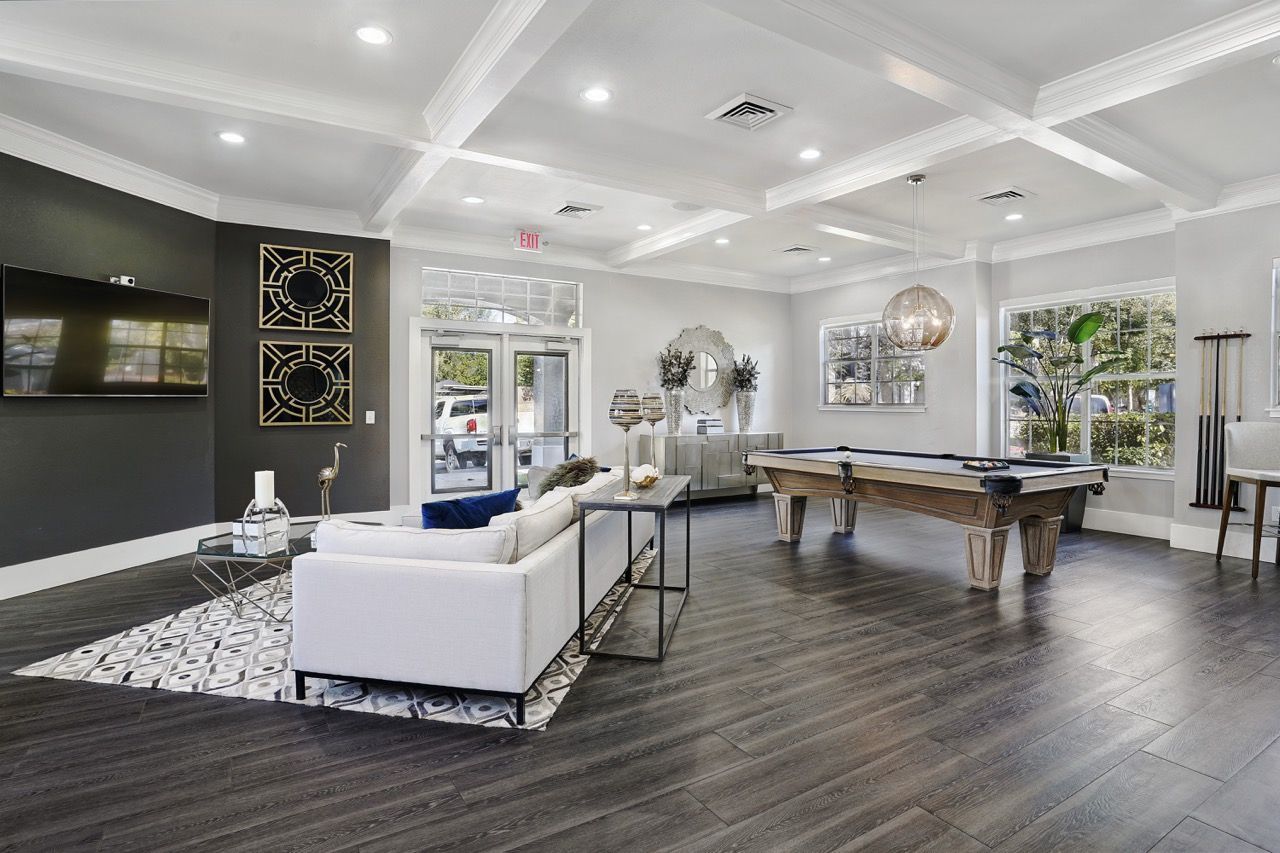 Bright, modern resident lounge with white sofa, pool table, and large windows