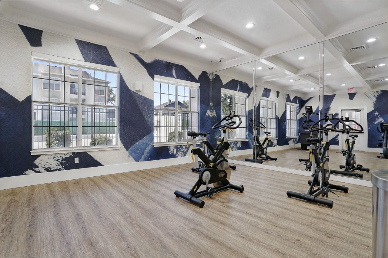Indoor fitness center with stationary bikes and mirrored wall.