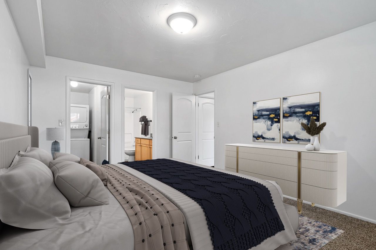 Bedroom in a modern apartment with a large bed, dresser, and open doorway to laundry.