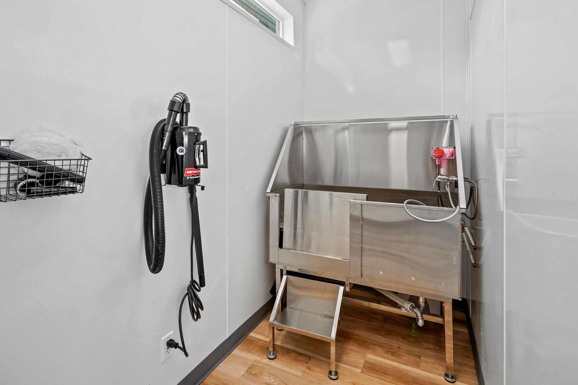 Dog grooming station with stainless steel tub, step, and dryer mounted on white wall at Preston Hollow in Millcreek, UT.