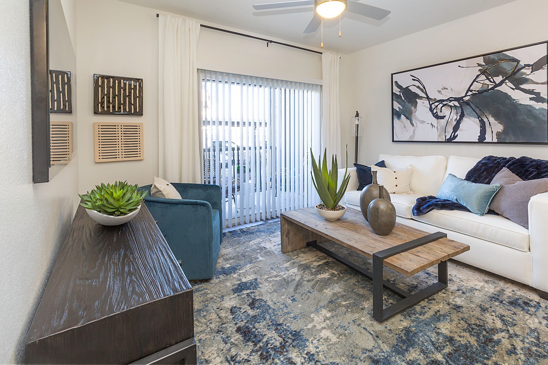 Living room with a white couch, blue armchair, and a wooden coffee table at Preston Hollow in Millcreek, UT.