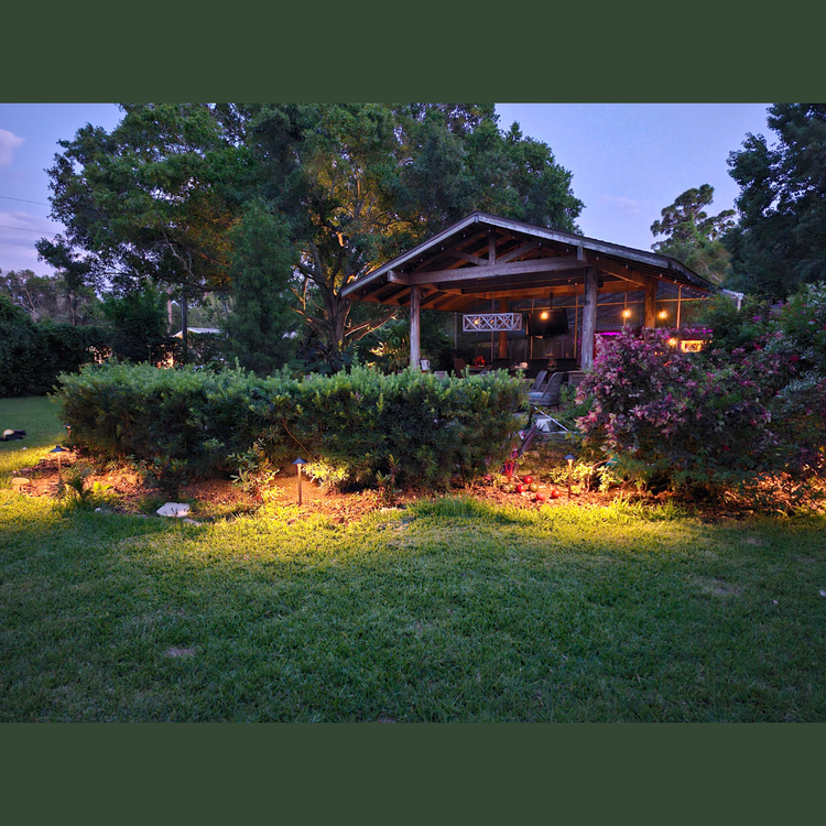 A house with a gazebo in the backyard is lit up at night
