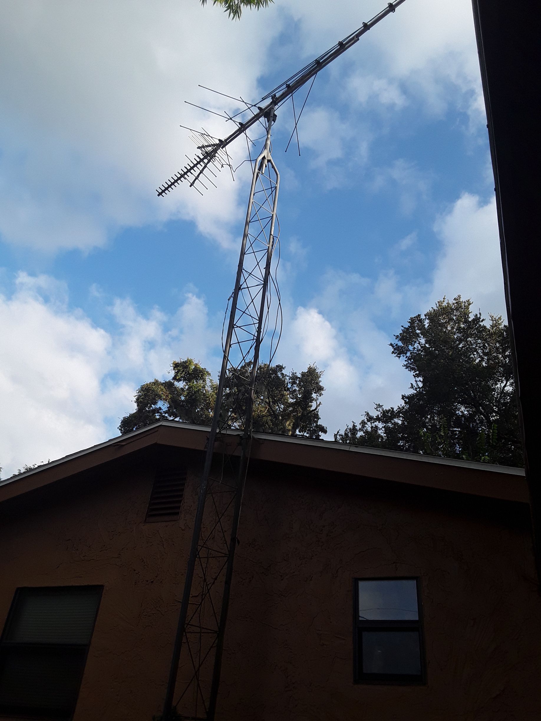 A large antenna is hanging from the roof of a house