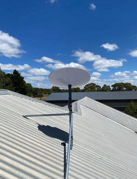A satellite dish is sitting on top of a white roof.