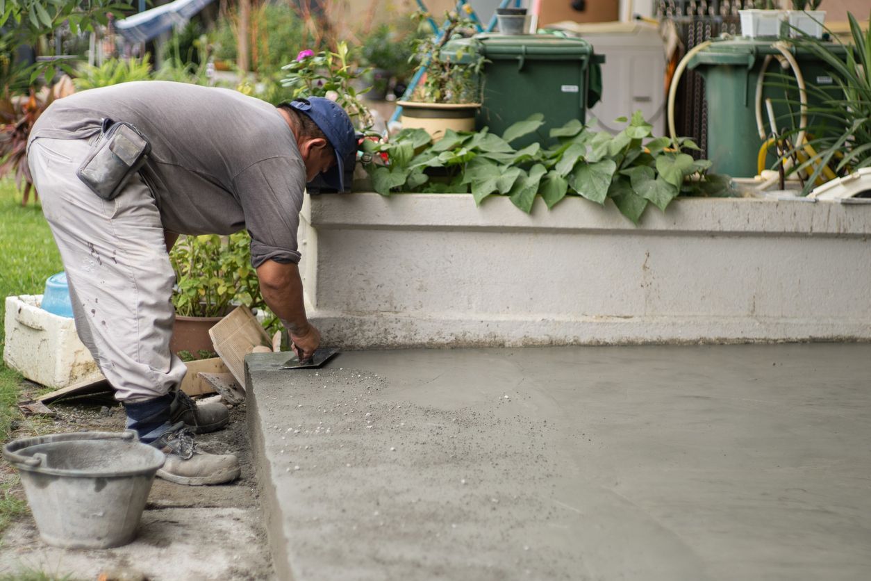 A man is laying concrete on a patio with a trowel.