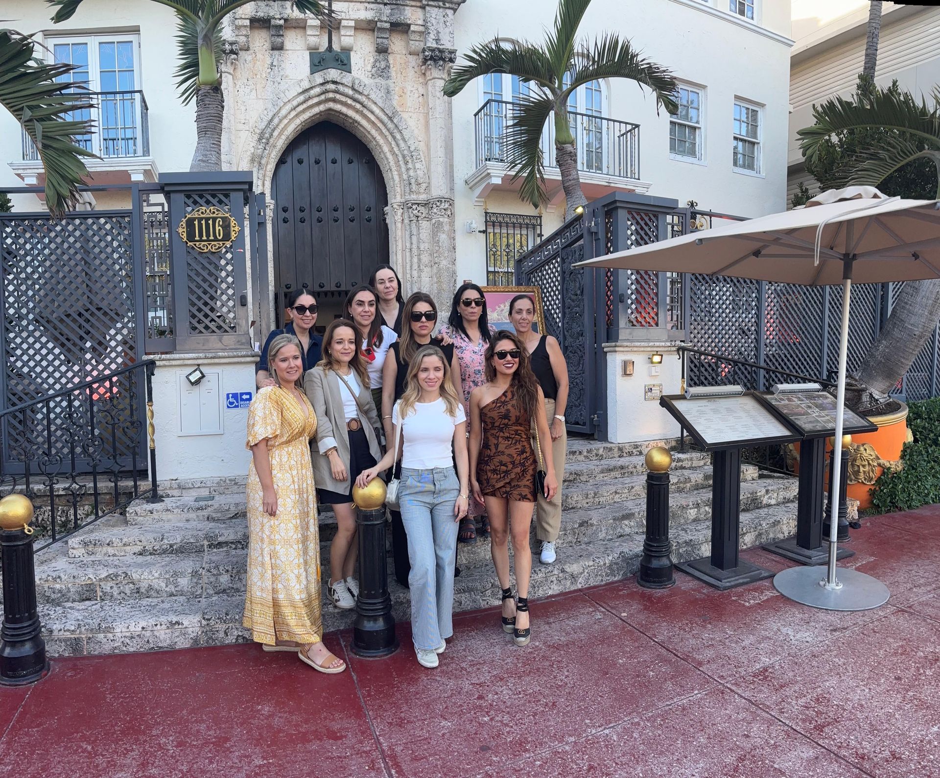 Group of women posing in front of the historic Versace Mansion on Ocean Drive in South Beach during the Miami Private City Tour.