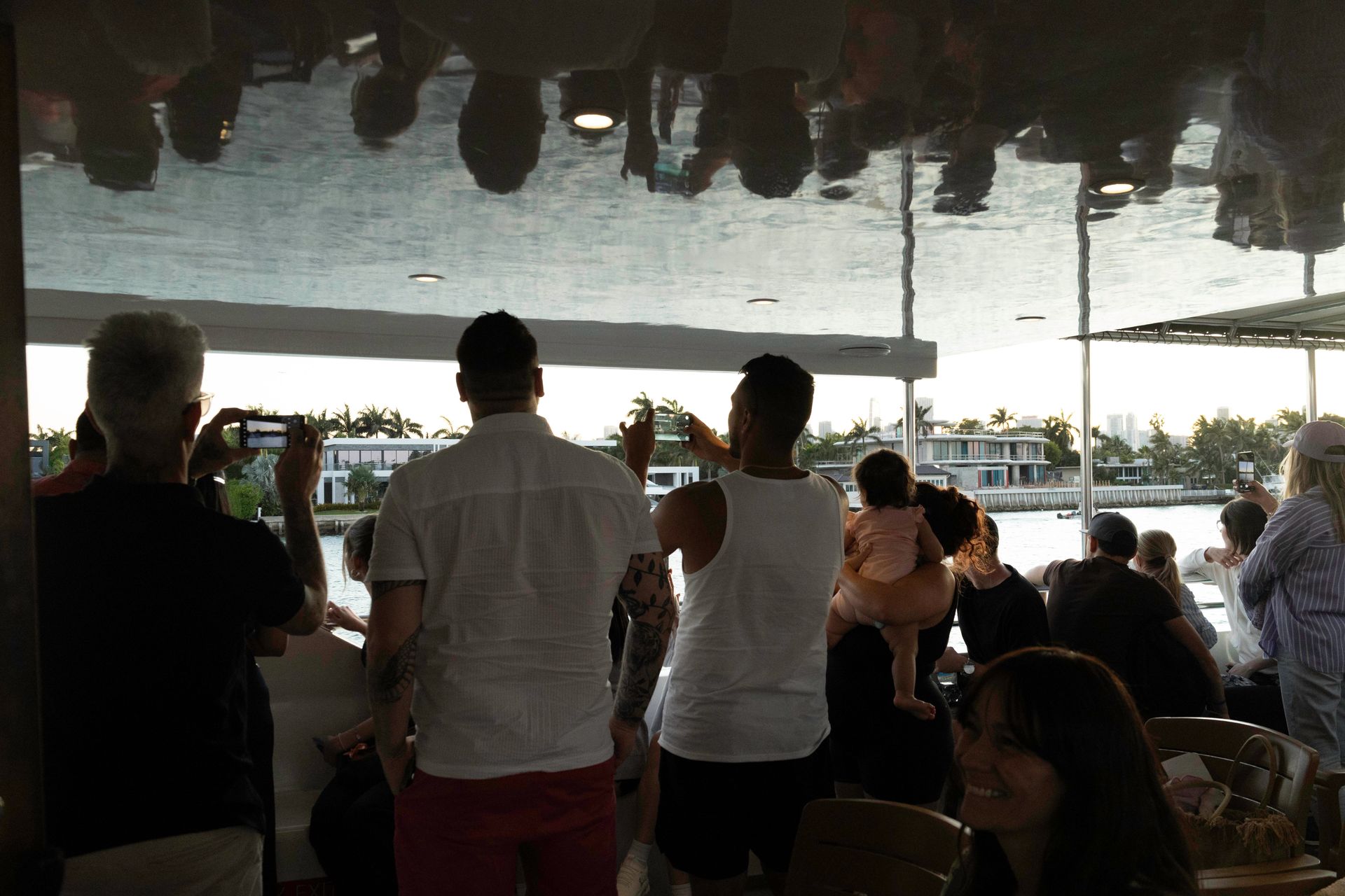 Passengers on the top deck of a Miami sightseeing cruise taking photos of celebrity mansions—some used Bayside boat tour discount codes, others paid full price