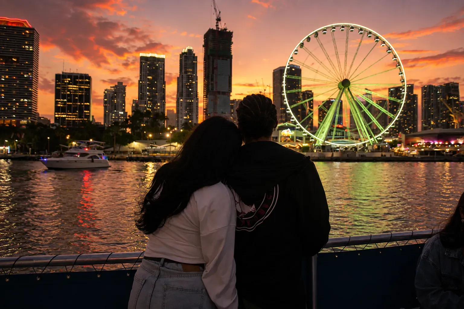 Couple enjoying a Miami sunset cruise with the Downtown skyline and illuminated Bayside Ferris wheel