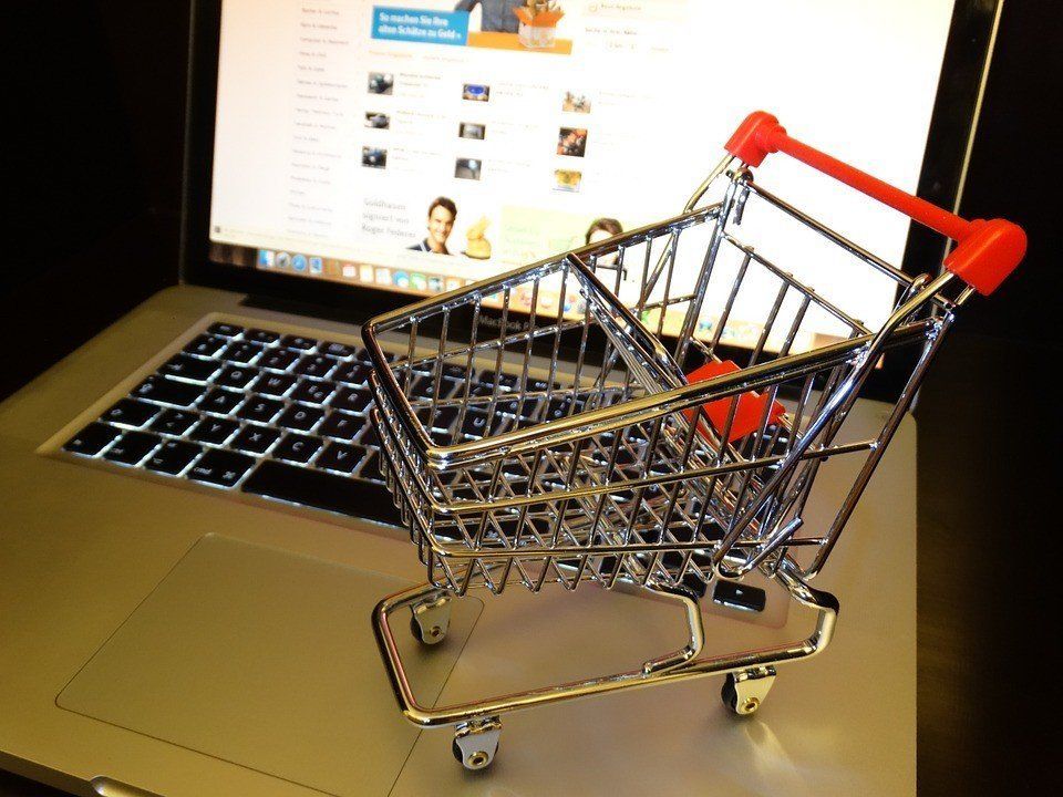 A small shopping cart is sitting on top of a laptop