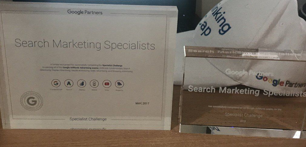 A search marketing specialist certificate is sitting on a table next to a trophy.