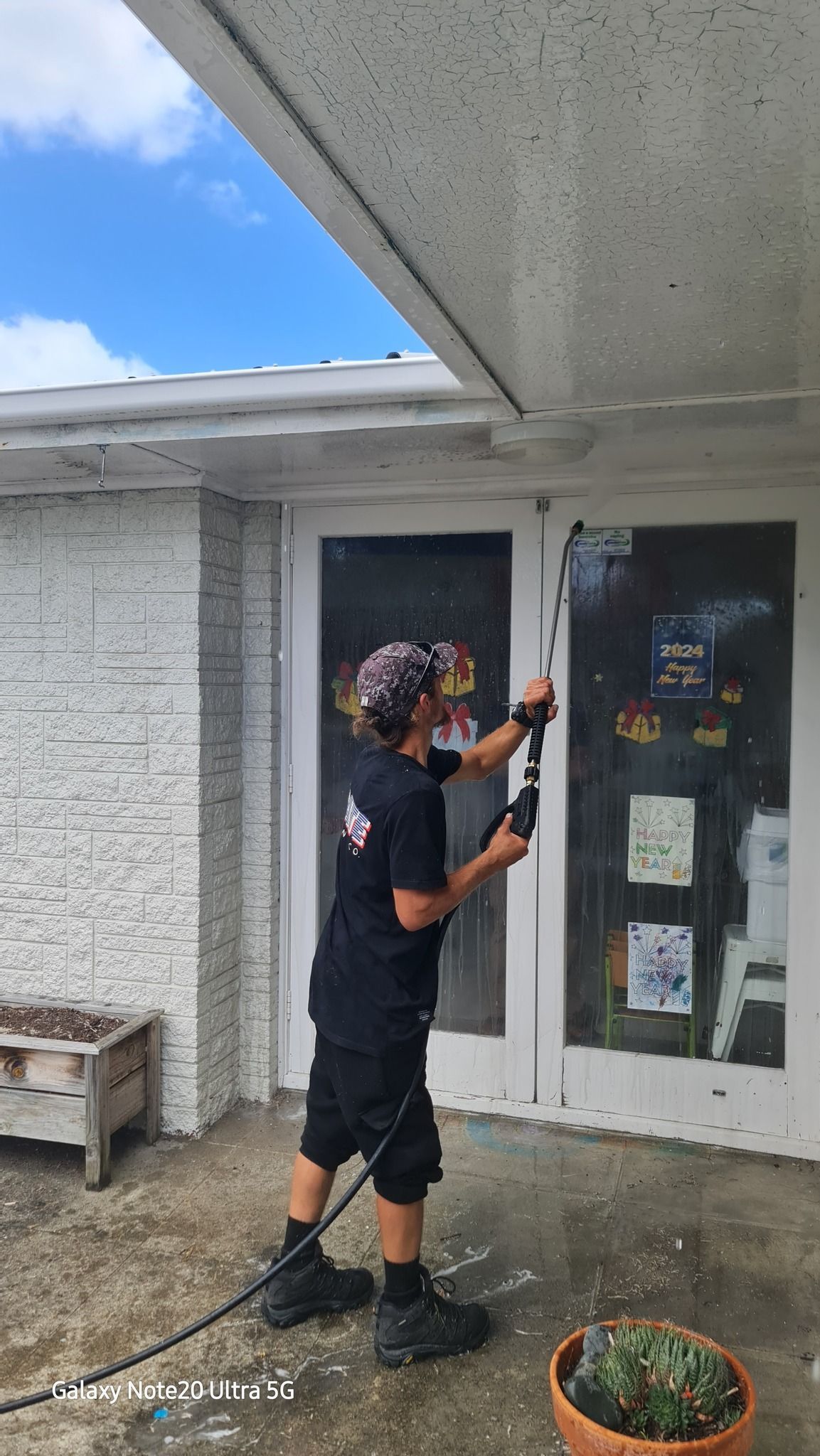 A Man Is Cleaning a Door with A High Pressure Washer - Auckland, NZ - Auckland Wash & Go Limited