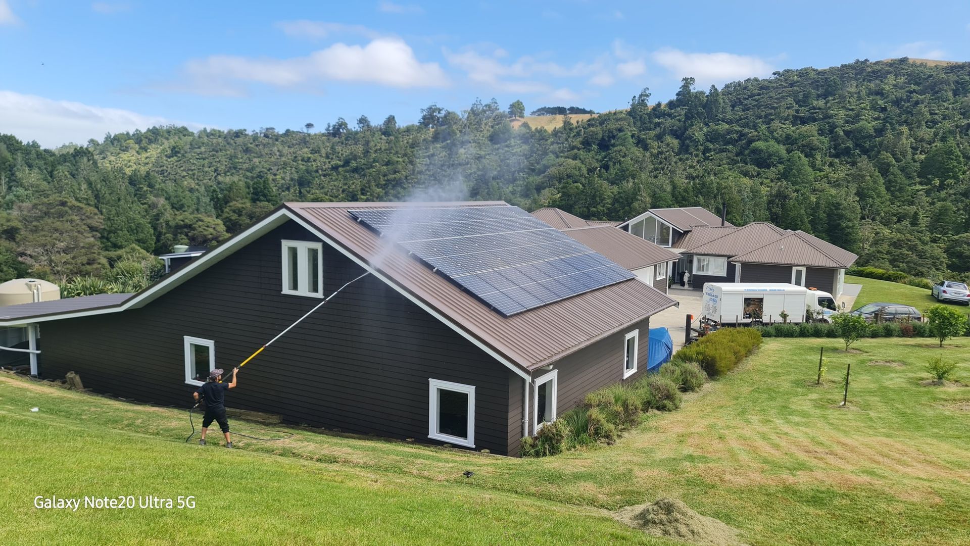 A Man Is Cleaning the Roof of A House with A Pressure Washer - Auckland, NZ - Auckland Wash & Go Limited