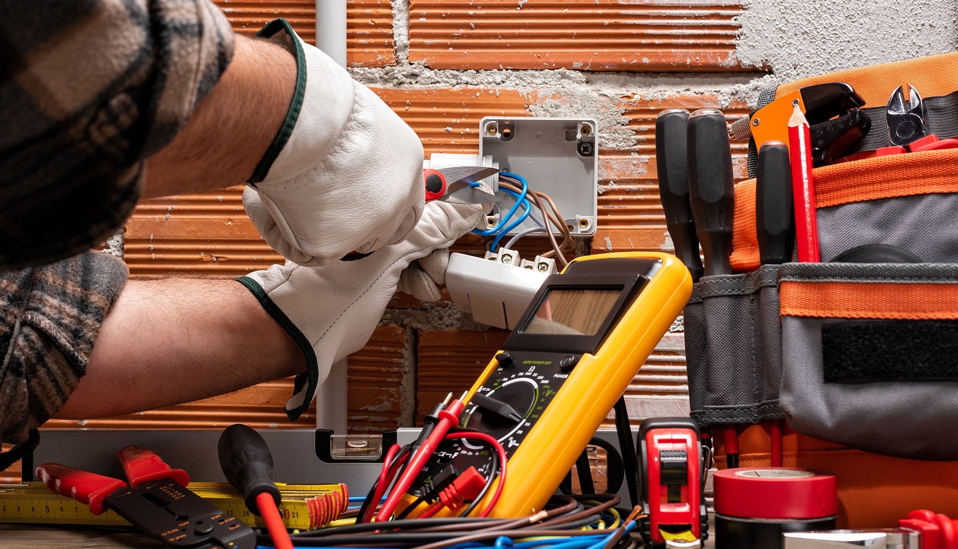 Electrician working on wiring in a brick-walled setting. 