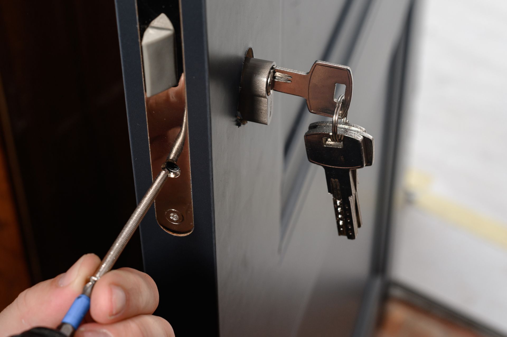 A locksmith unlocking a door with tools and a key in the lock.