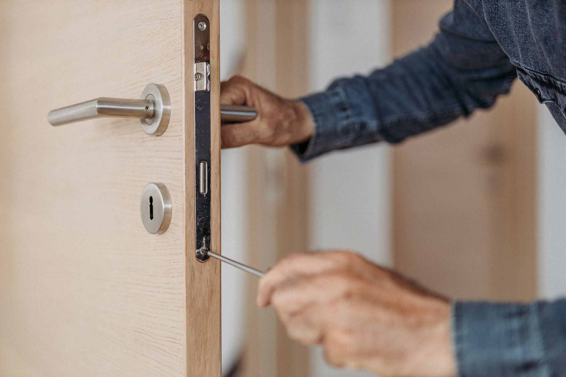 Person using a screwdriver to adjust a door lock mechanism.