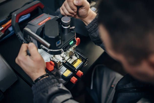 A locksmith, performing FOB automotive key duplication, making a car key copy on a modern machine.