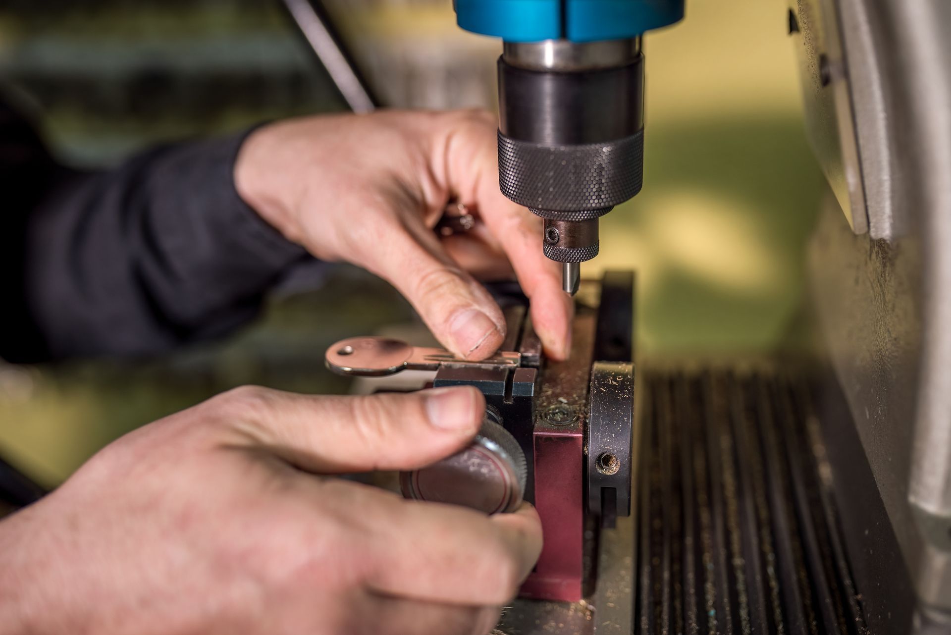 Close-up of a locksmith's hands carefully operating a key duplicating machine