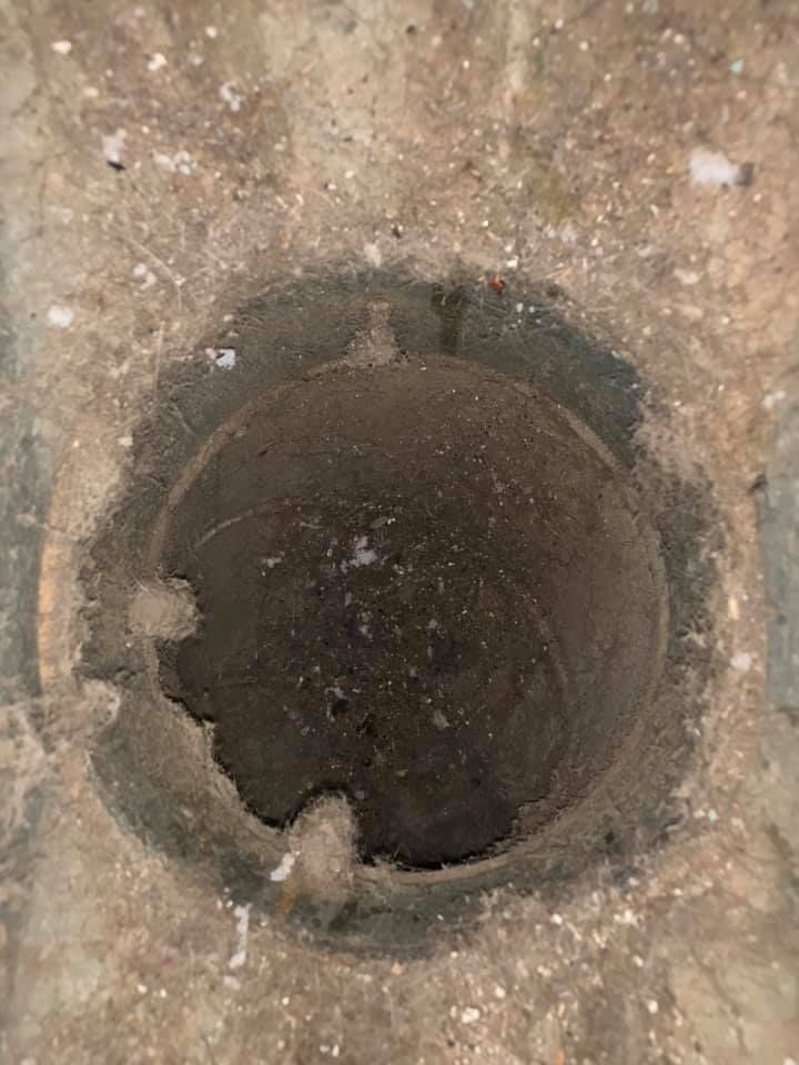 Circular dark drain opening in a concrete surface.
