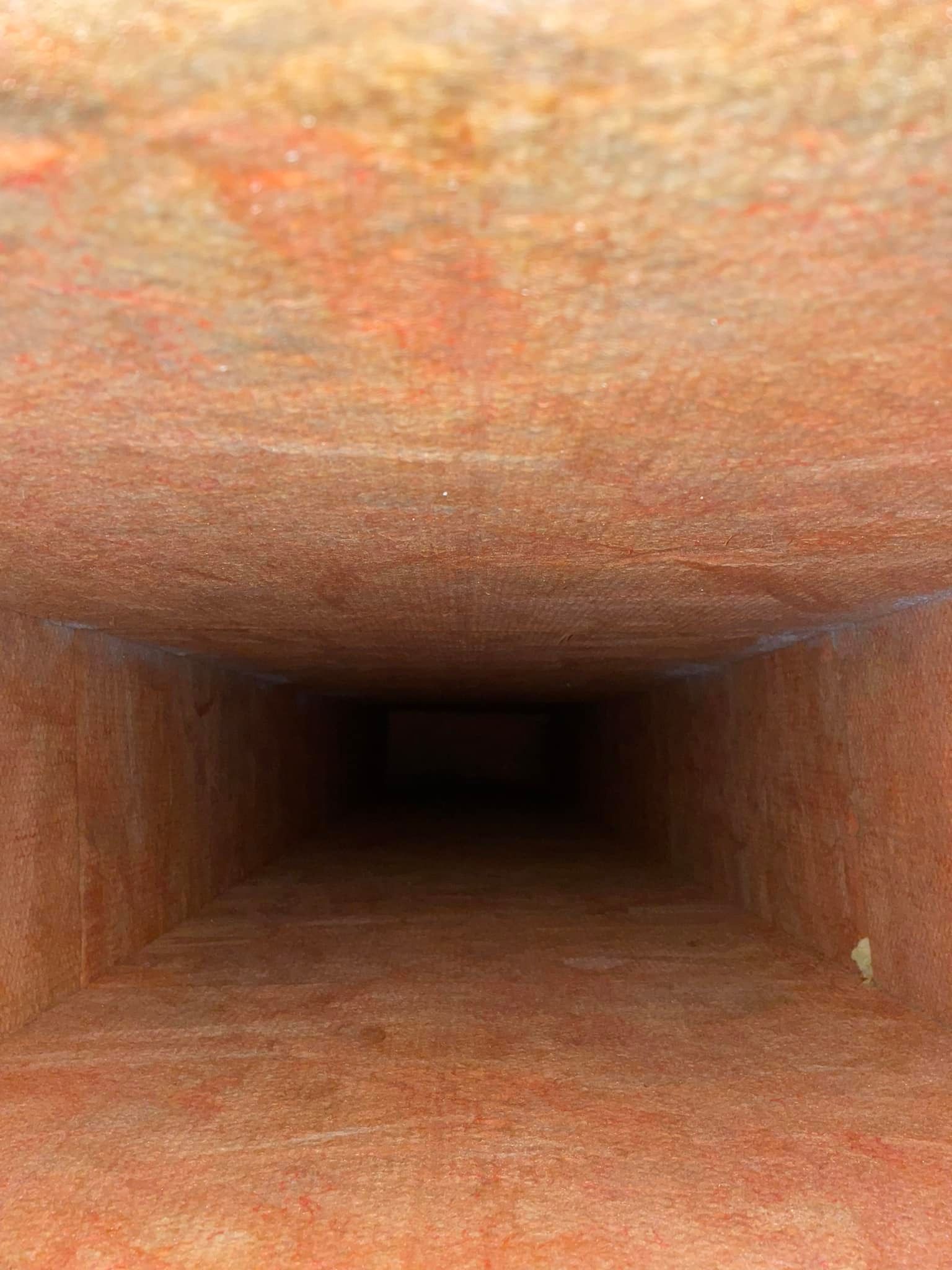 Looking down a long, dark, rectangular tunnel with reddish-brown walls.