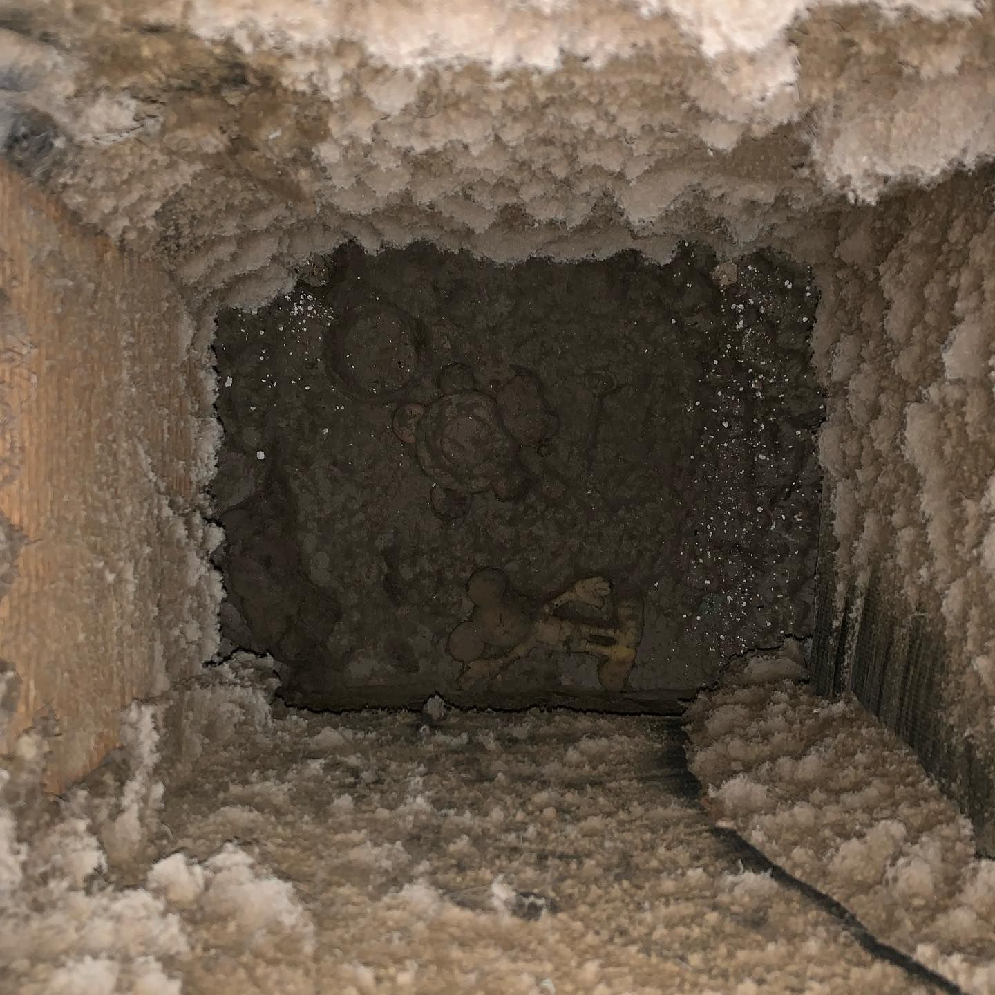 Inside view of a dusty air vent covered in white and grey buildup.