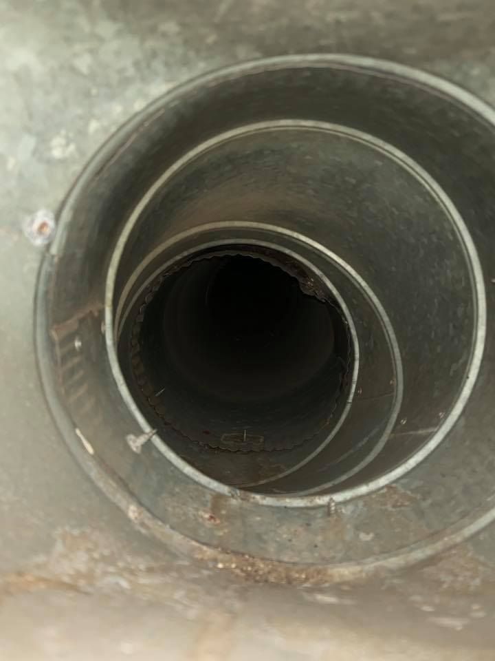 Inside of a metal air vent, spirals inward to a dark center. Brown debris is visible.