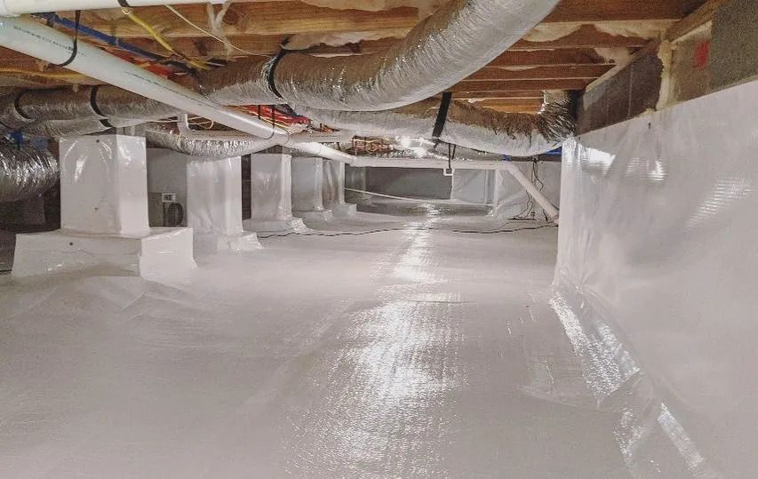 Crawl space with white vapor barrier, support columns, ductwork, and pipes.