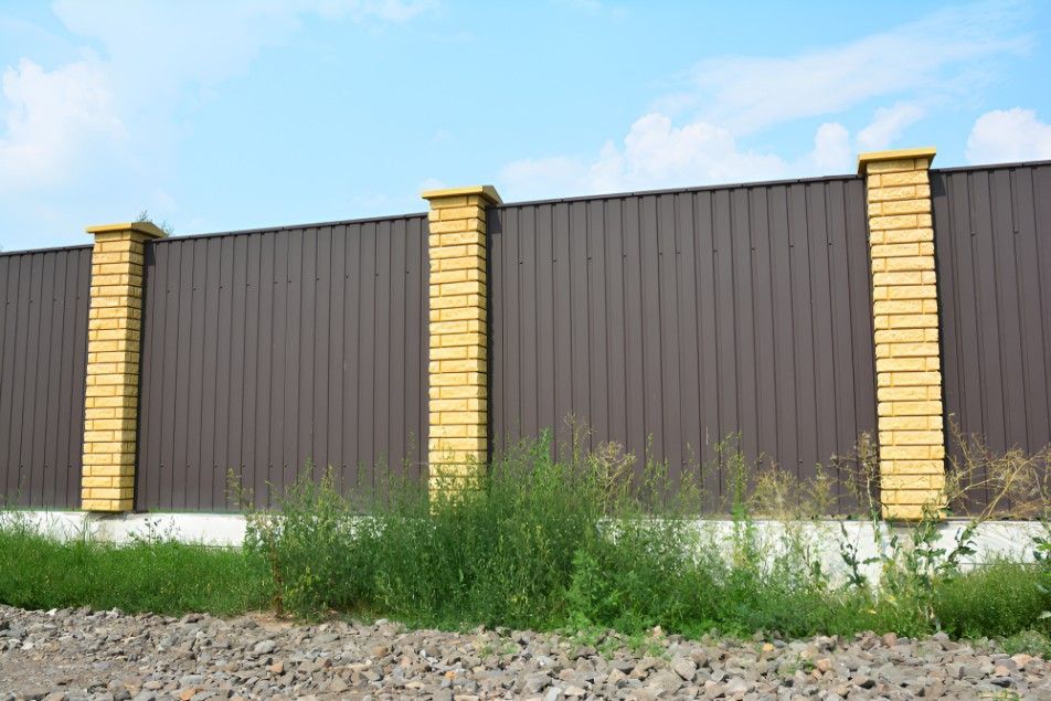 A Brown Metal Fence With Yellow Brick Pillars — Harbour Fencing In Moonee Beach, NSW