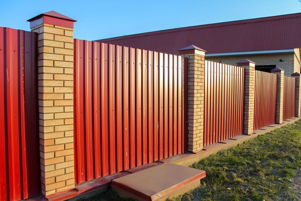 A Red Fence With Brick Pillars in Front of a House — Harbour Fencing In Nambucca Heads, NSW
