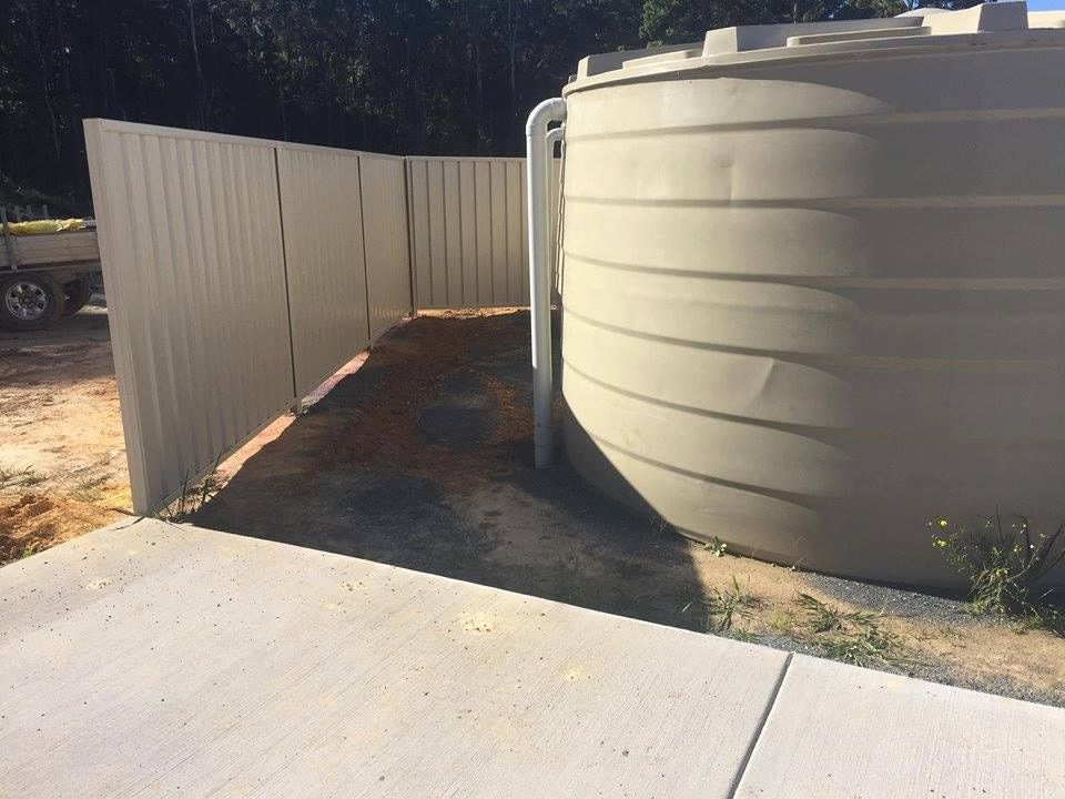 A Large White Tank is Sitting Next to a White Fence — Harbour Fencing In Moonee Beach, NSW