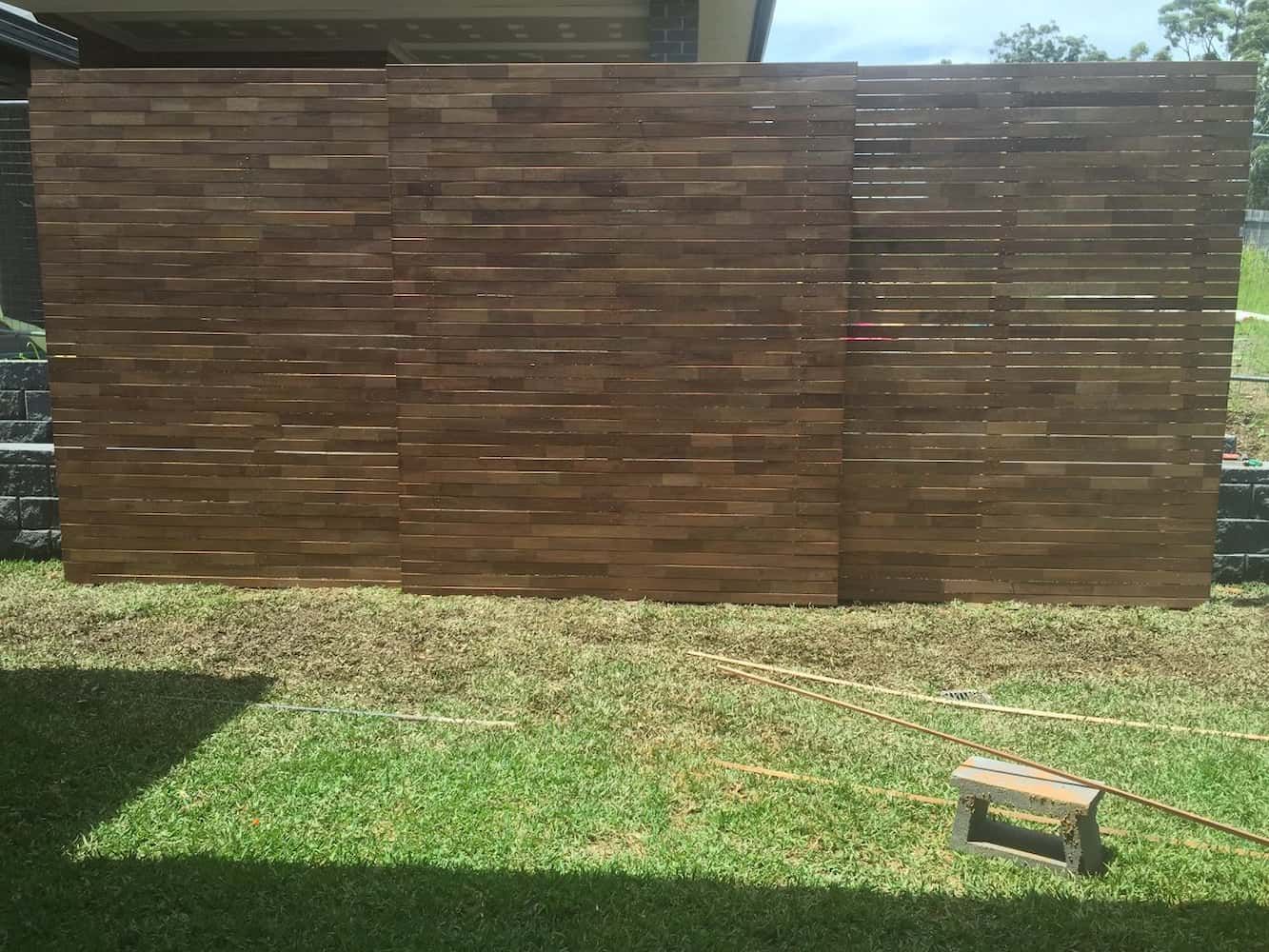 A Wooden Fence is Sitting on Top of a Lush Green Field — Harbour Fencing In Moonee Beach, NSW